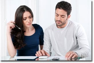 Man and woman working on paperwork with a calculator.